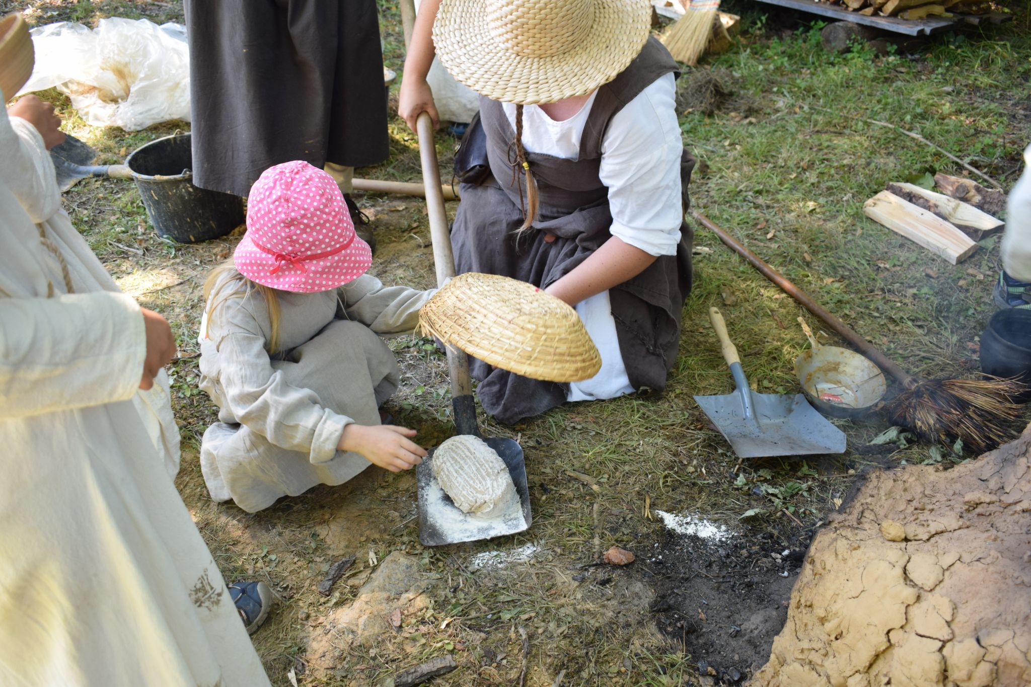 Děti pečou vlastní chléb v replice středověké pece, kterou si postavily.