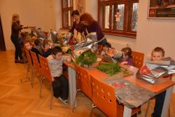 Účastníci workshopu tvoří vánoční aranžmá z chvojí. 